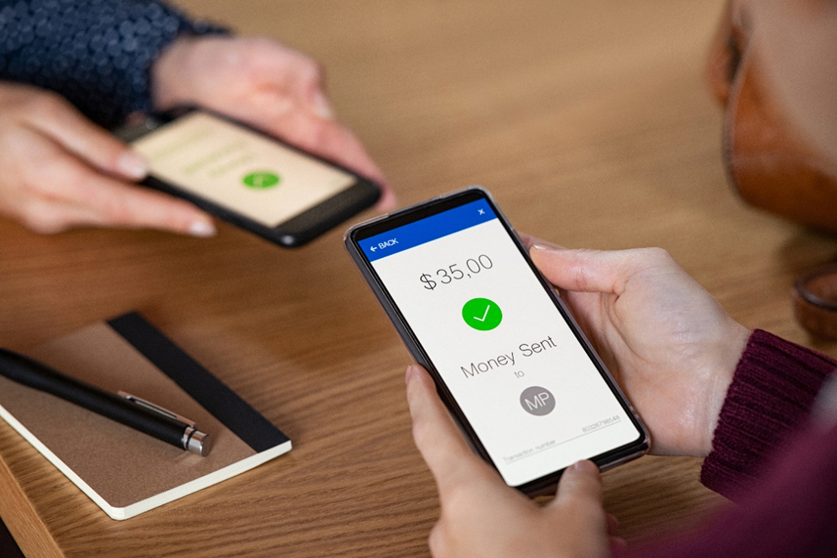 Celular en las manos de una persona que miestra un envío exitoso de dinero